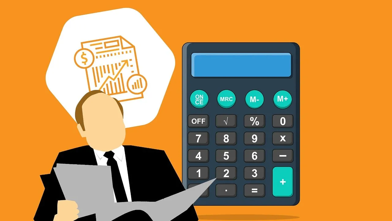 A close-up of an accountant working at a calculator and laptop